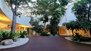 Un ampio giardino interno con un percorso curvo, circondato da diverse piante e alberi.