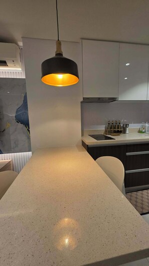 A kitchen with a central island, a pendant light, and a marble backsplash. - Tambuli Tower C Unit 5D (Lapu-Lapu)