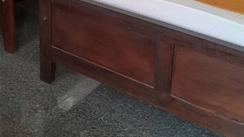 Une chambre d’hôtel avec trois lits en bois, chacun doté d’un matelas blanc et d’une couverture orange.
