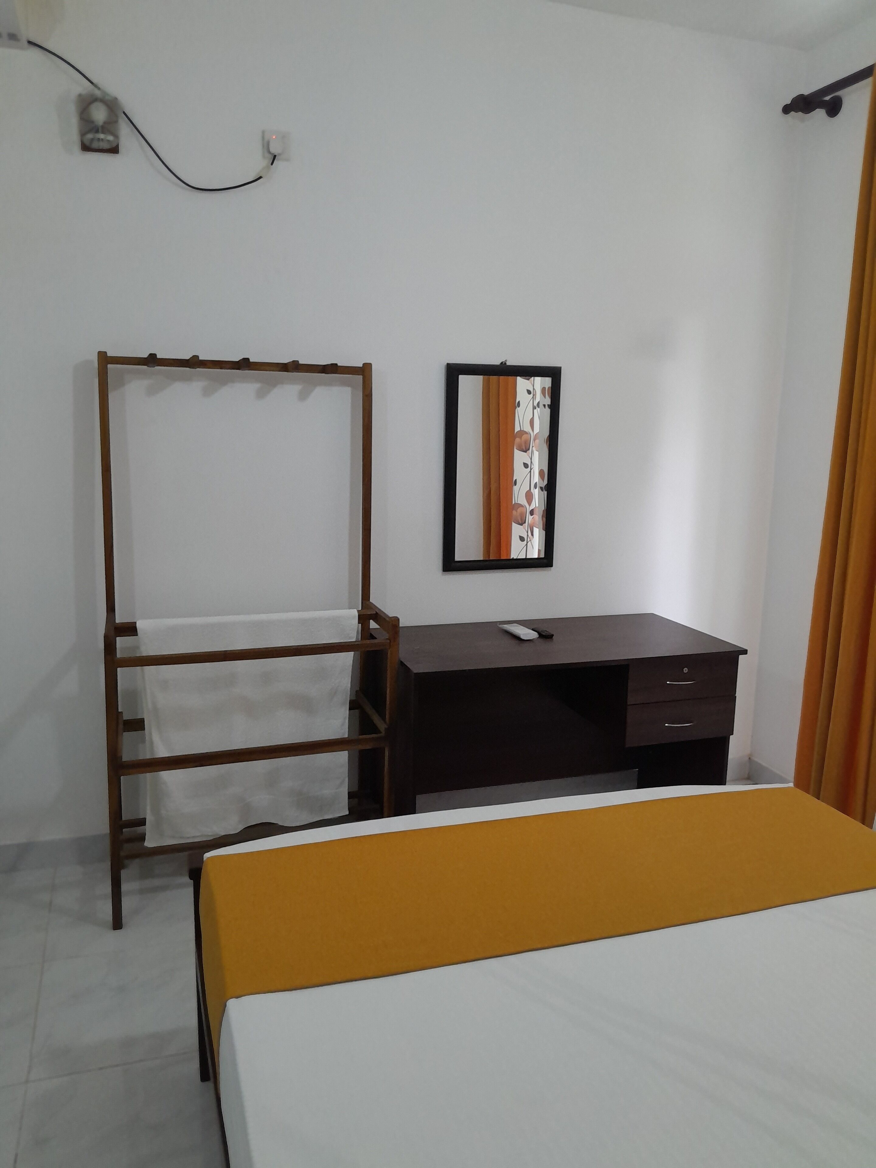 Un dormitorio con una cama, un armario de madera, un escritorio, un espejo y una cortina.