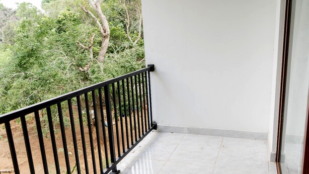 A balcony with a black metal railing, white walls, and a tiled floor. - Lake wind villa (Anuradhapura)