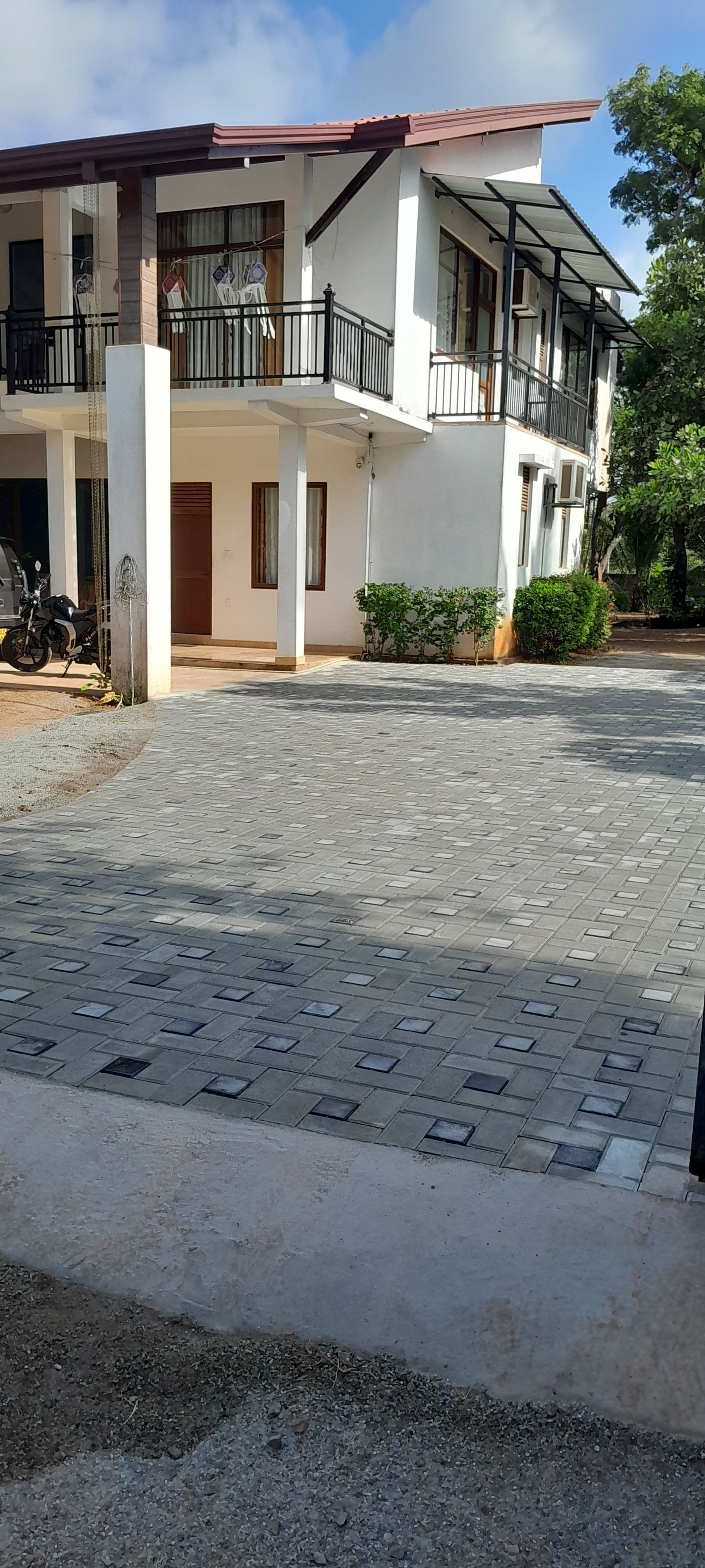 A two-story building with a paved driveway and a motorcycle parked in front.