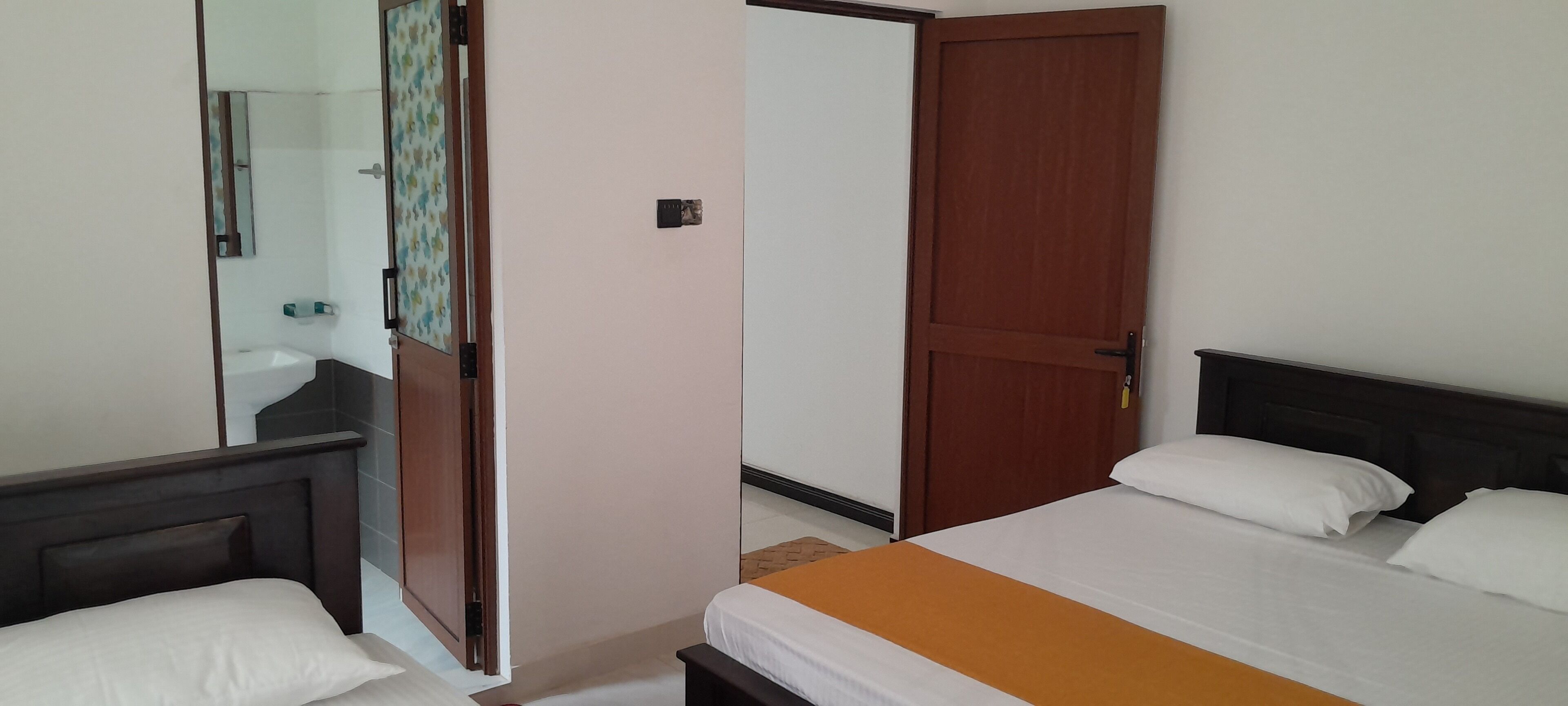 Quarto de hotel com uma cama, mesa de cabeceira, espelho e guarda-roupa.