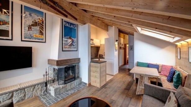A cozy interior with a fireplace, wooden furniture, and a colorful sofa. - Views of Bruson & Petit Combin range from the top floor of the Alpine residence (Val de Bagnes)