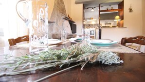 A dining table with a clear pitcher, plates, and a rustic stone fireplace in the background. - Olive House by Frangki (Aegina)