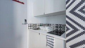 A modern kitchen with white cabinets, a black and white patterned backsplash, a stainless steel sink, and a hanging red towel rack. - WS Hôtel de Ville - Musée Pompidou (Paris)