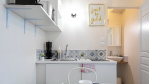 A modern kitchen with white cabinets, a marble countertop, and a dining area with a table set for four. - WS Champs Elysées - Ponthieu (Paris)