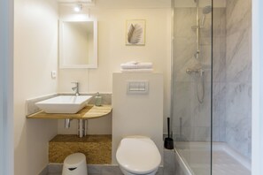 Un baño con lavamanos, inodoro y ducha blancos.