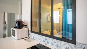 A kitchen with a microwave, coffee maker, and a window with a view of a room. - WS Champs Elysées - Ponthieu (Paris)