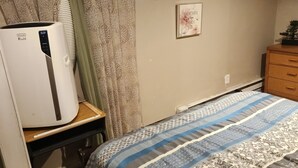 Une chambre à coucher comprenant un lit, un radiateur, une commode et deux œuvres d’art murales.