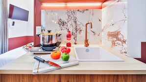 Cocina moderna con salpicadero de mármol, un lavamanos, una estufa y una encimera con tabla de cortar, tomates y un cuchillo.