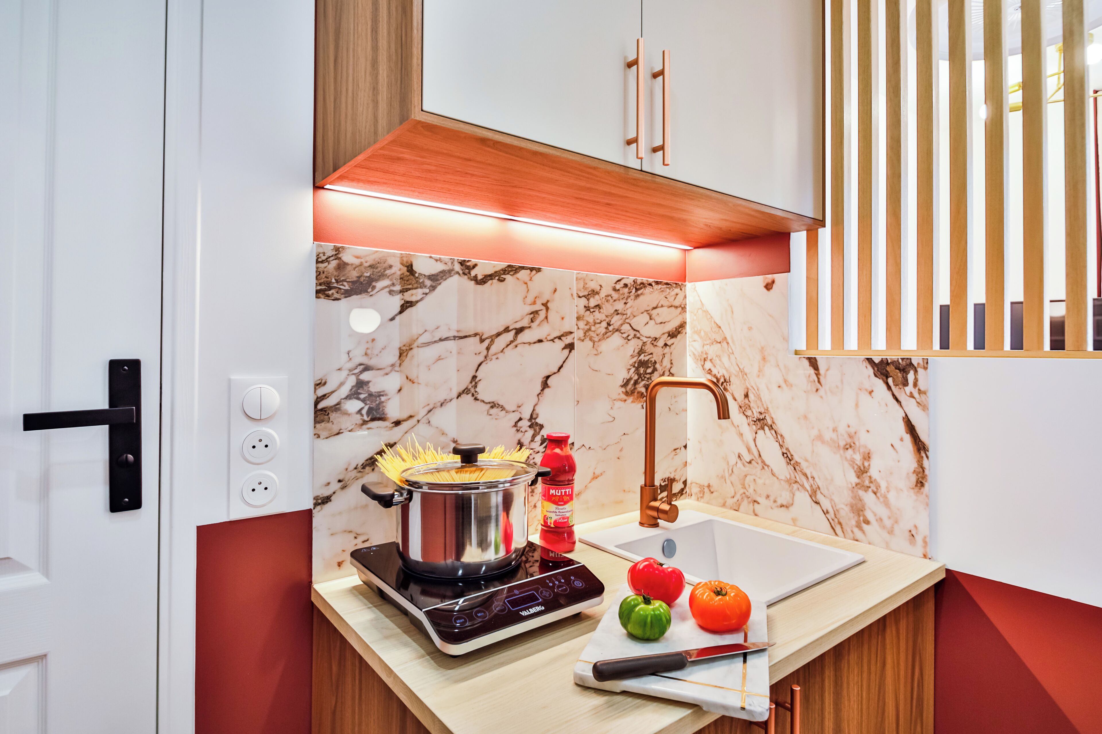 A modern kitchen with a built-in stove, a sink, and a marble backsplash.