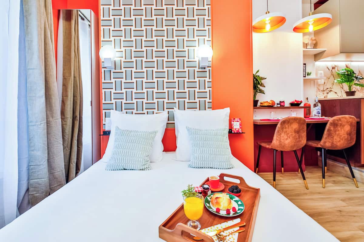 A hotel room with a bed, breakfast tray, and a dining area with chairs and a table.