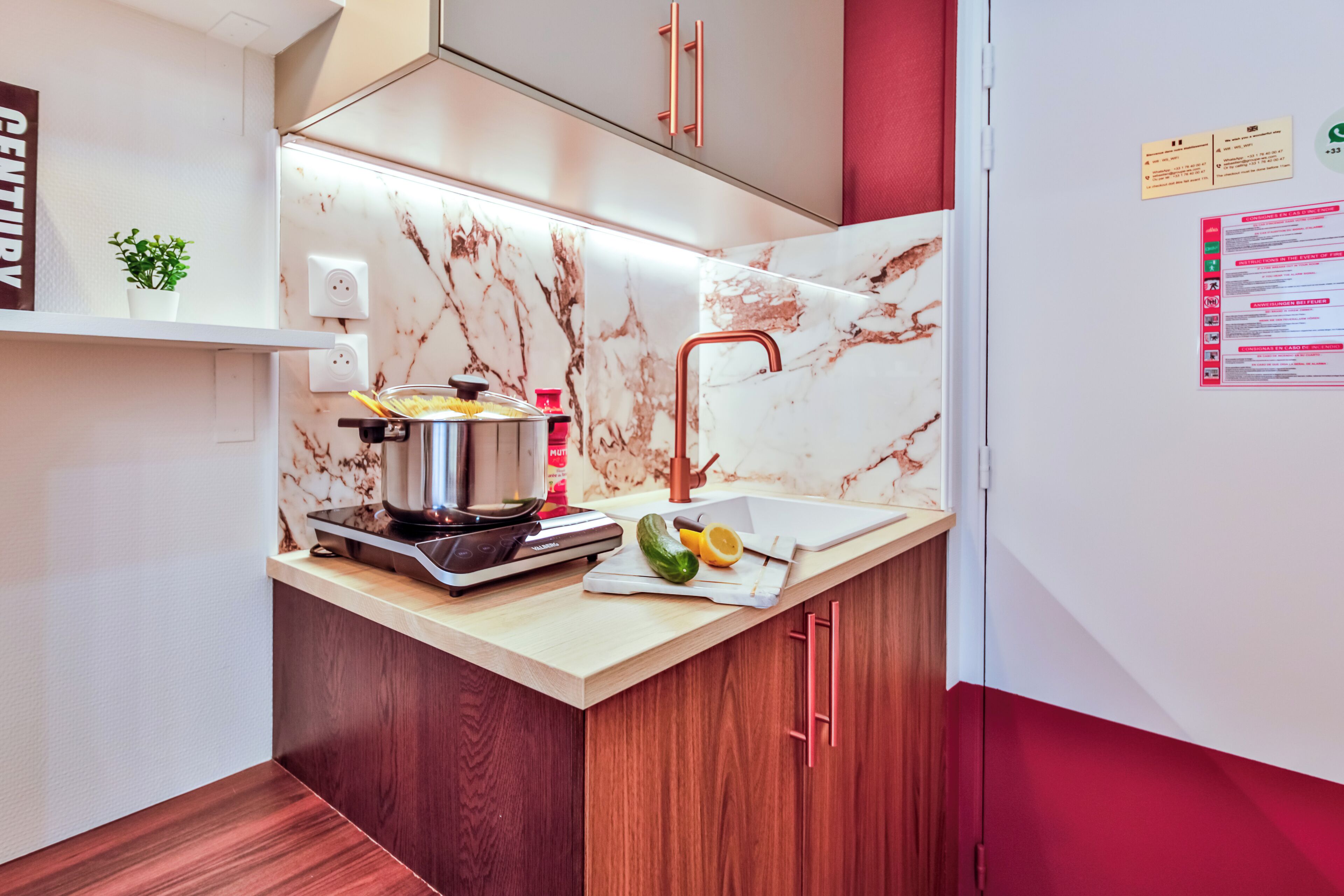 A modern kitchen with a marble backsplash, wooden cabinets, and a copper faucet.