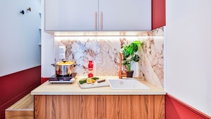 A modern kitchen with wooden cabinets, a marble backsplash, a sink, a stove, and a potted plant.