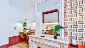 A modern kitchen with a marble countertop, a built-in oven, and a red accent wall.