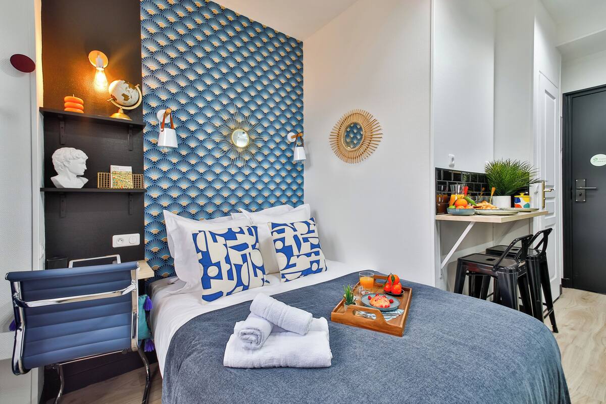 A modern hotel room with a bed, a desk, and a chair.