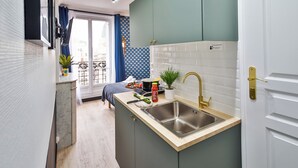 A modern kitchen with a sink, countertop, and a view of the city through a large window. - WS Tour Eiffel - Laos (Paris)