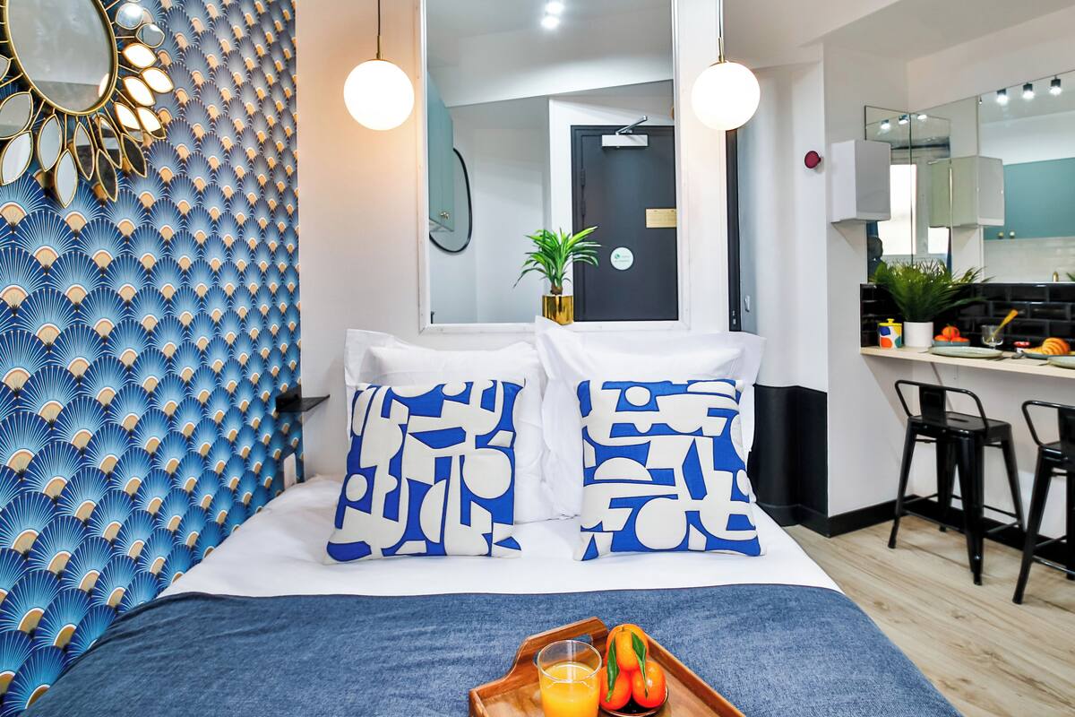 A modern hotel room with a bed, a breakfast bar, and a small kitchenette.