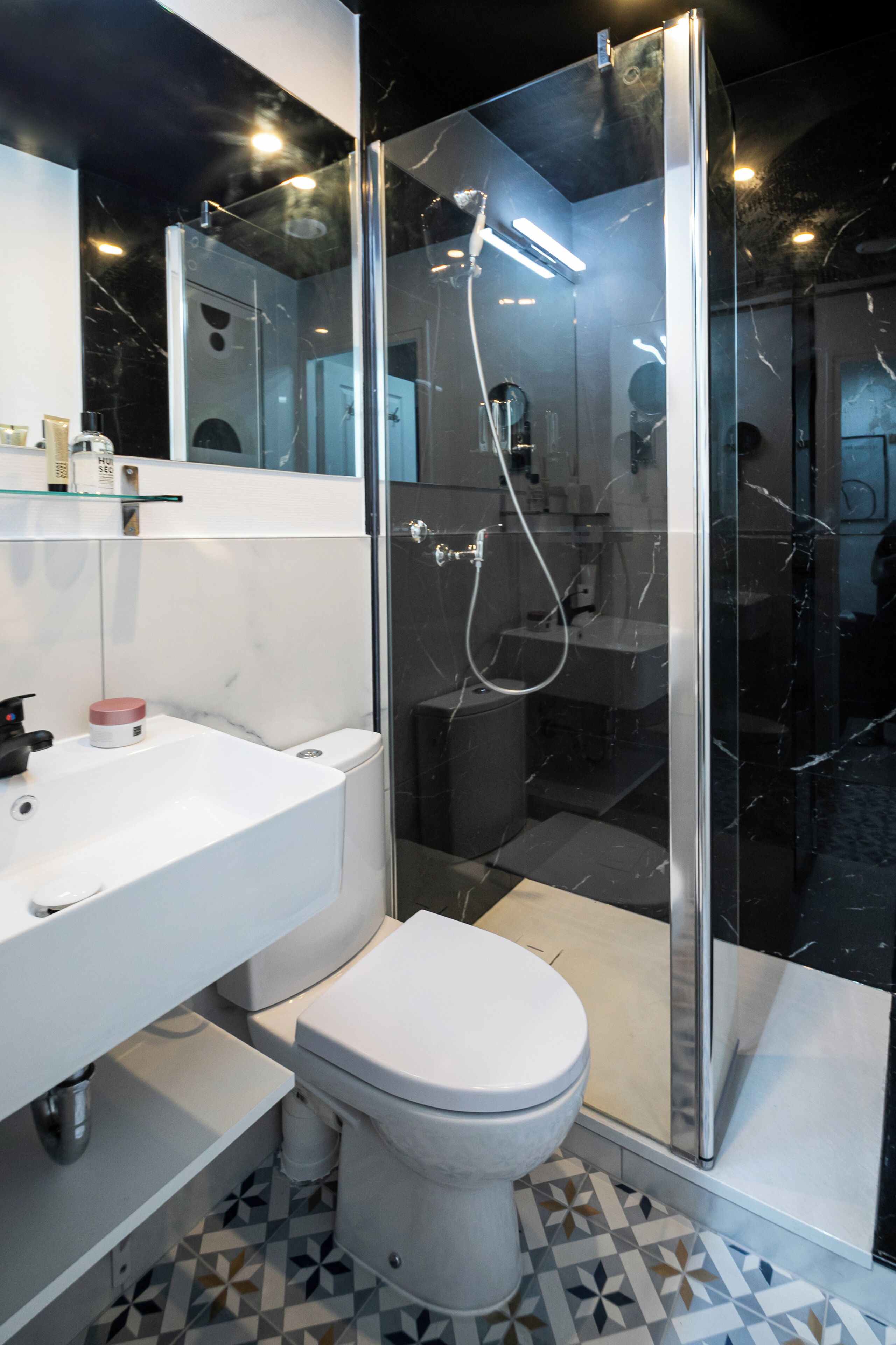 A modern bathroom with a glass-enclosed shower, a white sink, and a toilet.