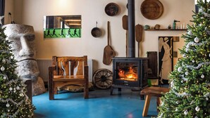 A cozy living room with a stone fireplace, wooden furniture, and Christmas decorations. - Korte Hotel Sleeps 14 With Courtyard (Mestia)