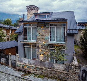 A modern two-story house with stone accents and large windows. - Korte Hotel Sleeps 14 With Courtyard (Mestia)