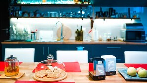A bar area with a variety of bottles and glasses on the shelves, a coffee machine, and a wooden table with a tea set, napkins, and fruits. - Korte Hotel Sleeps 14 With Courtyard (Mestia)