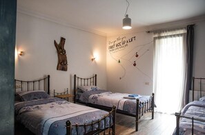 A bedroom with two single beds, a wooden wall decor, a motivational quote, and a window with curtains. - Korte Hotel Sleeps 14 With Courtyard (Mestia)