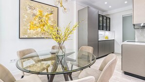 A modern dining area with a glass table, cushioned chairs, and a vase with yellow flowers. - Solaga - Cinteria (Málaga)