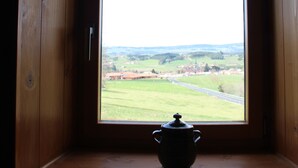 A small wooden room with a window offering a view of a green landscape and a road. - Stone and wood house (Saint-Pal-de-Chalencon)