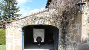 A stone building with a covered entrance and a bicycle parked inside. - Stone and wood house (Saint-Pal-de-Chalencon)