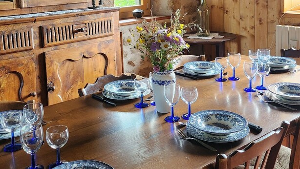 A rustic dining room with a wooden table set for a meal, surrounded by stone walls and wooden beams. - Stone and wood house (Saint-Pal-de-Chalencon)