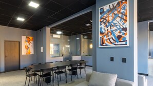 Una sala de reuniones moderna con una gran mesa, sillas, un sofá y arte abstracto en las paredes.