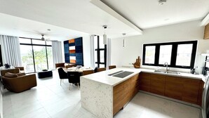 A modern kitchen with a central island, wooden cabinets, and a large window. - Welcome N/H Villa Paradise in enchanting Reading, Montego Bay with AC, Gym, WiFi (Reading)