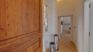 Een houten garderobe, een gang met een houten vloer, en twee brandende kandelaars.