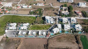 Vista aérea de una zona residencial con casas modernas, piscina y un campo verde.