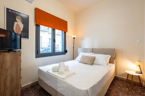 Ein Hotelzimmer mit einem Bett, einem Schreibtisch, einer Lampe und einem Fenster mit Blick auf die Straße.