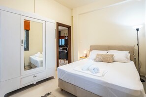 Une chambre d’hôtel comprenant un lit, une armoire, une table de chevet avec une lampe, et une vue sur l’extérieur par une fenêtre.