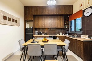 Une cuisine moderne avec des meubles en bois, une table à manger avec des chaises et une horloge au mur.