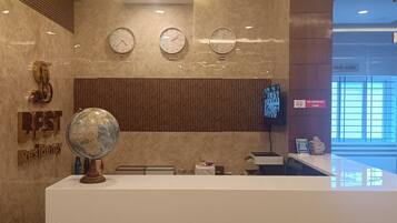 A reception desk with a globe, clocks, and a 'No Smoking' sign in a modern lobby.