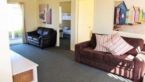 A room with a brown couch, a black leather chair, a white cabinet, and a bunk bed in the background. - Alton Seas 67 Hargreaves Rd, Middleton (Middleton)