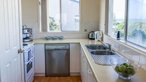 A compact kitchen with a dishwasher, a coffee machine, a kettle, and a sink. - Alton Seas 67 Hargreaves Rd, Middleton (Middleton)