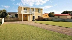 A two-story house with a balcony, a well-maintained lawn, and a clear sky. - Alton Seas 67 Hargreaves Rd, Middleton (Middleton)