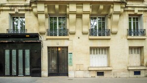 Un bâtiment doté d’un grand portail noir, de nombreuses fenêtres avec volets et d’un balcon orné de balustrades en métal.