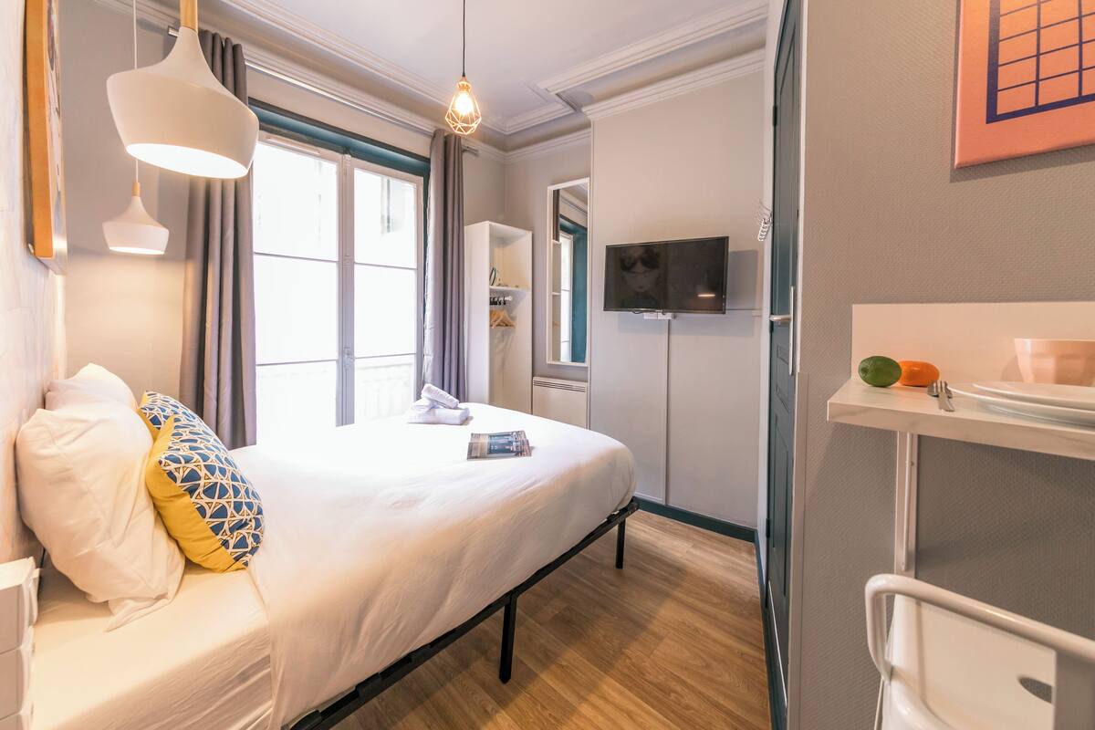 Une chambre à coucher avec un lit, une table de chevet et un téléviseur fixé au mur.