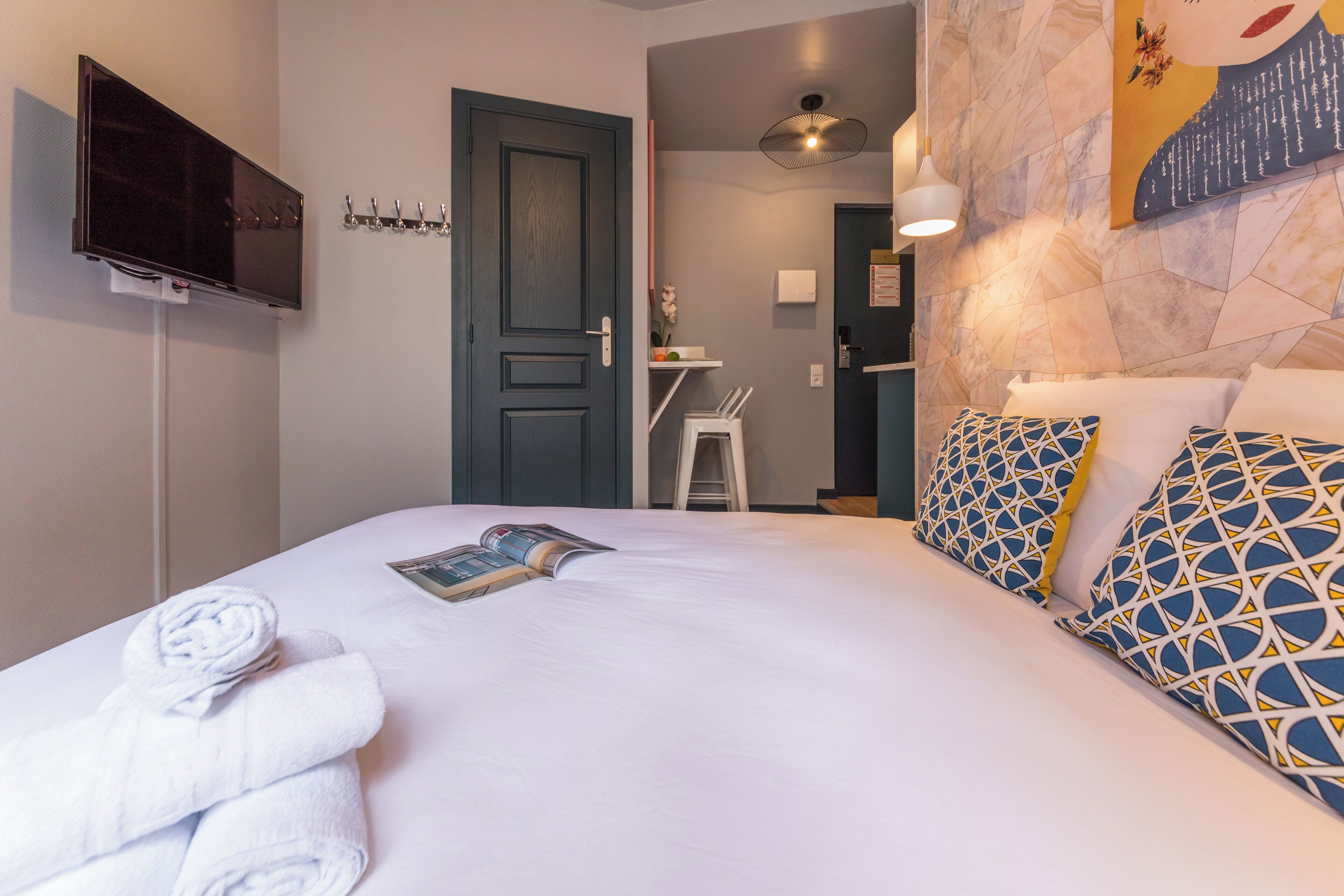 Een hotelkamer met een bed, een televisie, een deur en een schilderij aan de muur.