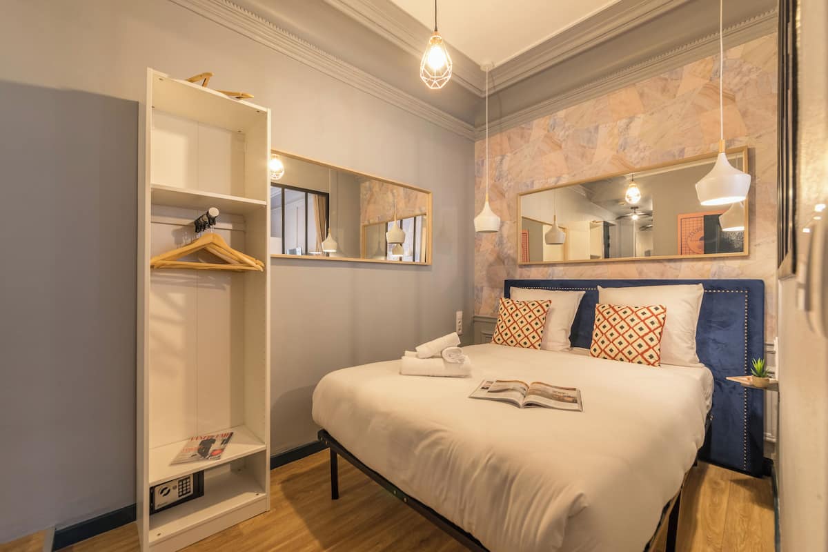 Une chambre bien rangée, avec un grand lit, une armoire et un miroir.