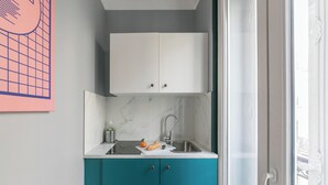 A compact kitchen with teal cabinets, a white countertop, and a marble backsplash. - WS Grands Boulevards - Opera (Paris)
