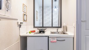 A compact kitchen with a built-in stove, a sink, and a window with a view of a brick wall.