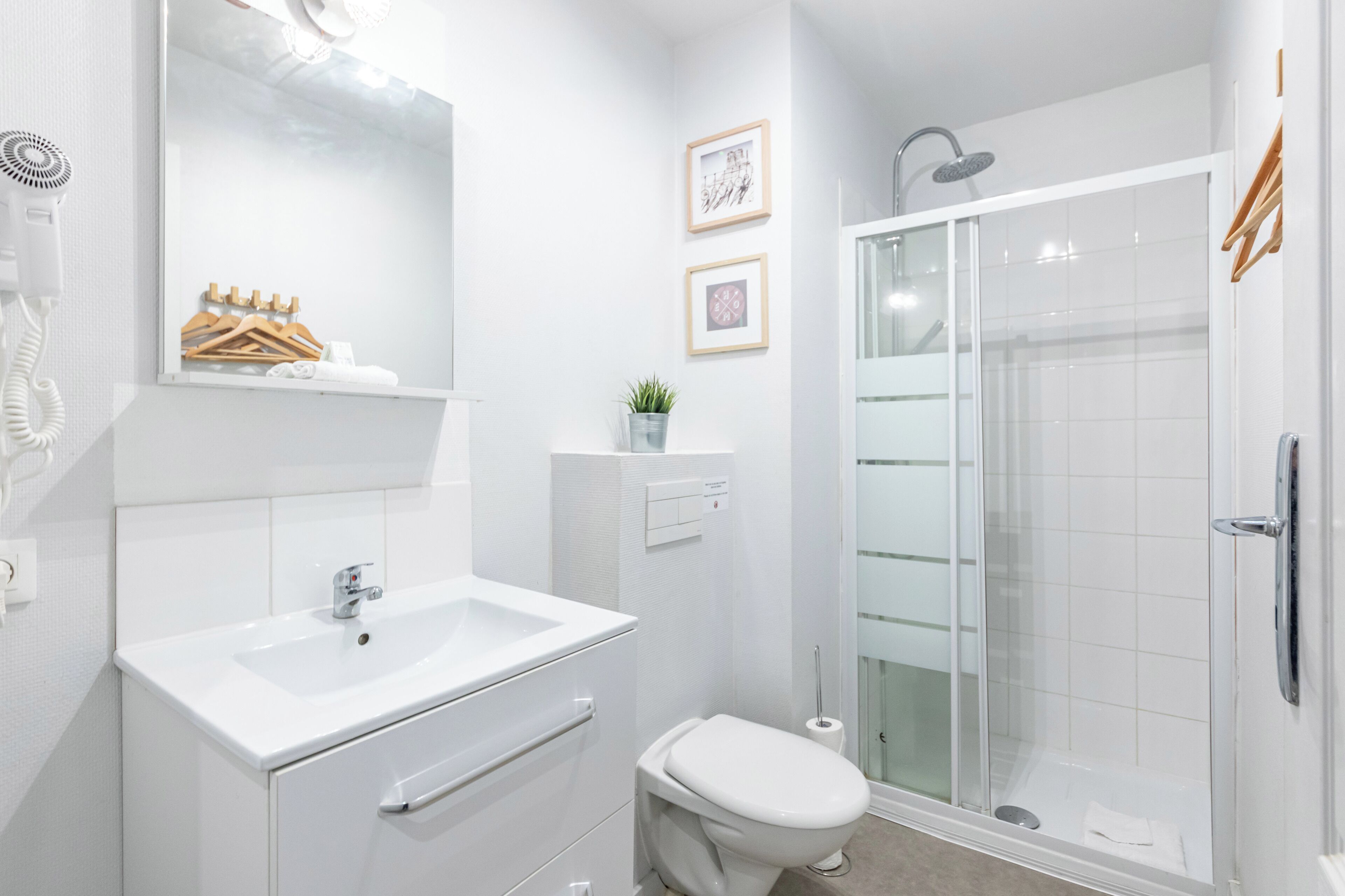 Une salle de bain moderne avec un lavabo blanc, des toilettes et une douche à parois de verre.